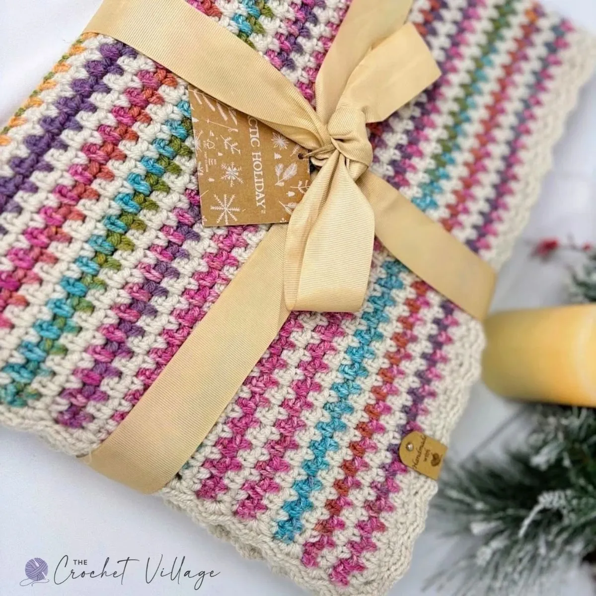 Crochet moss stitch blanket folded and tied with a gold ribbon as a handmade holiday gift