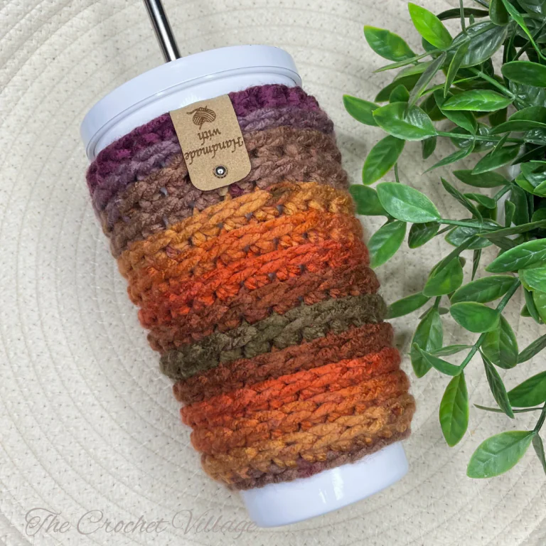 A cup with a straw wrapped in a colorful, simple crochet cup cozy,
