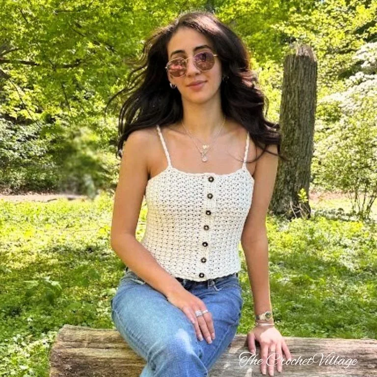 A young lady wearing a crochet tank top showing decorative buttons at the front.