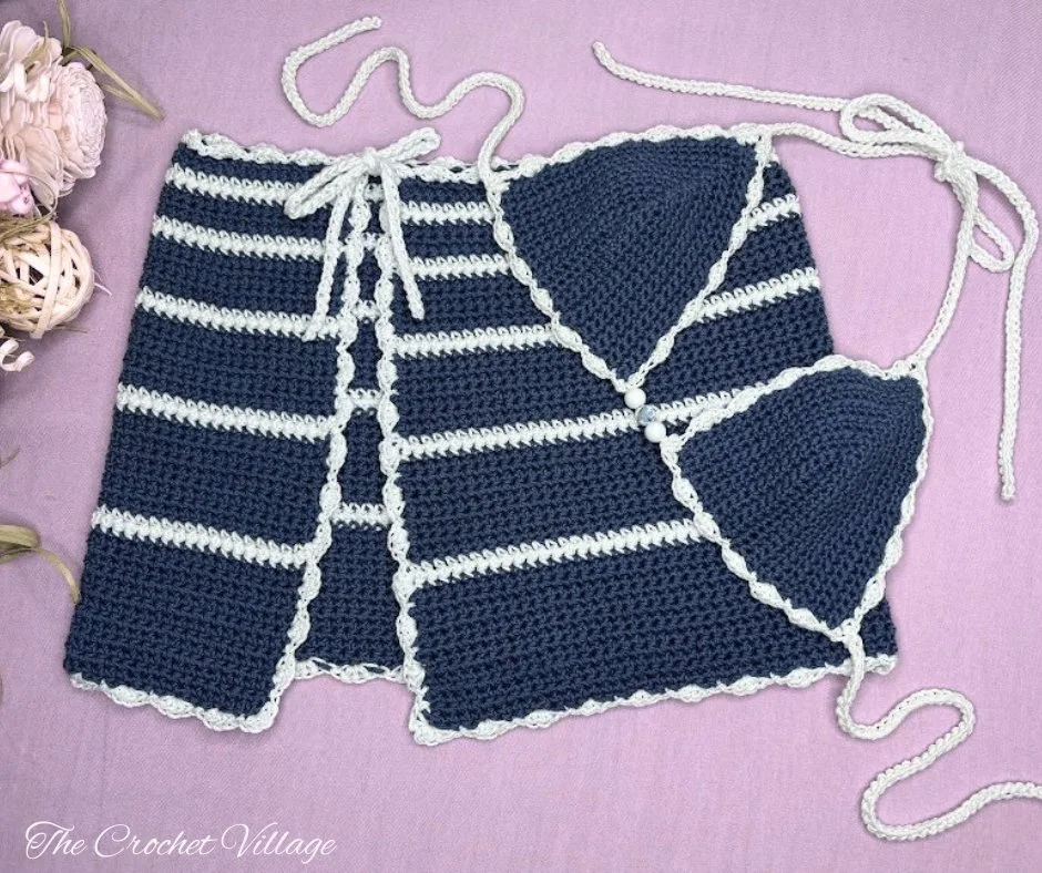 Crochet bikini top and matching crochet summer skirt displayed flat on a surface, decorated with flowers.
