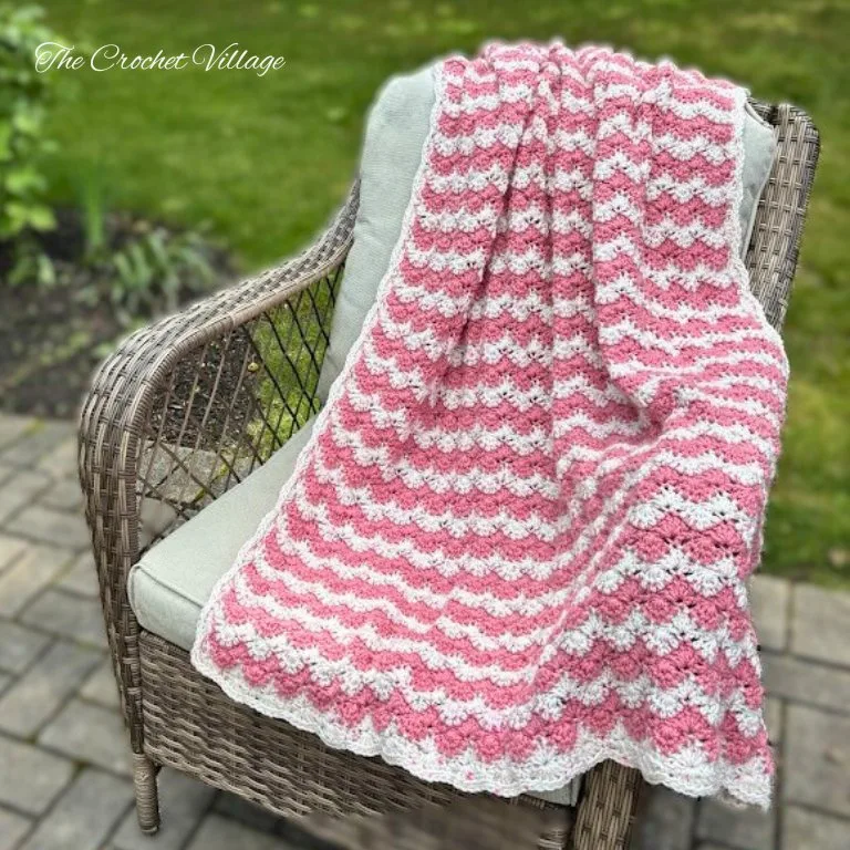 A gorgeous two-color blanket featuring a starburst stitch, draped over a chair outdoors