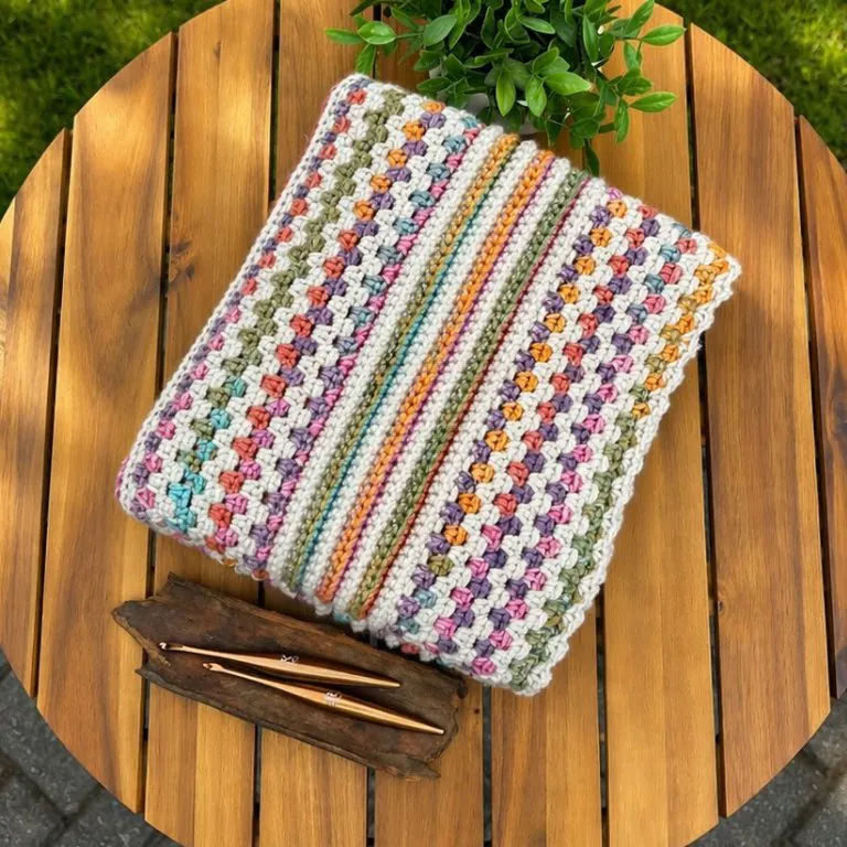 Reversible crochet blanket neatly folded featuring multicolor stripes, textured stitches, and a delicate edging – beginner-friendly and customizable crochet pattern.