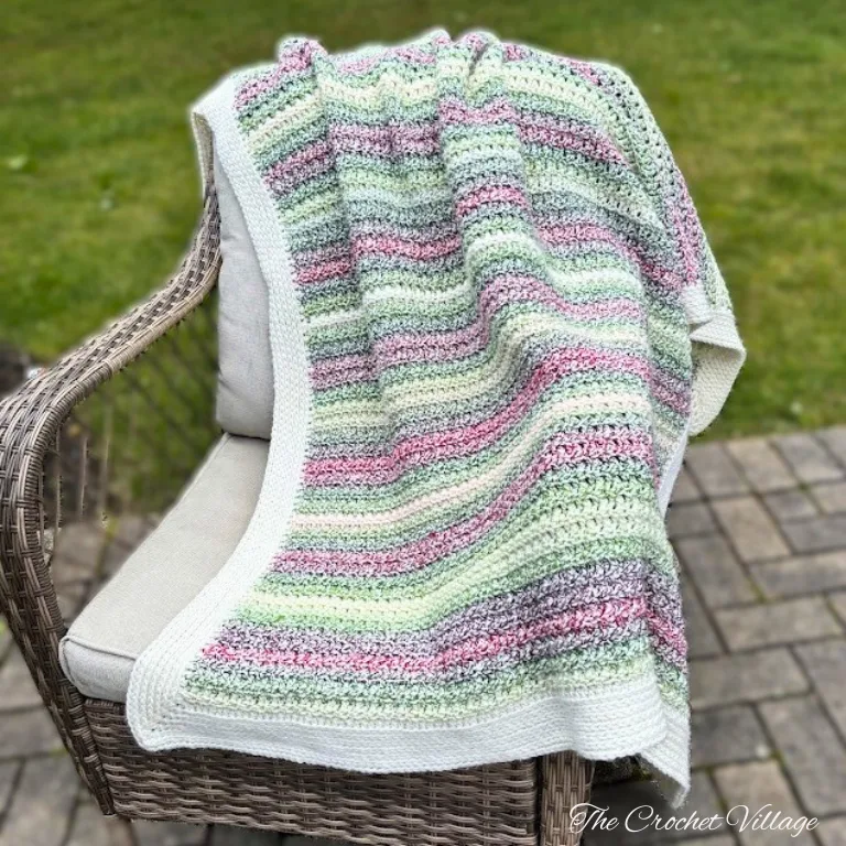 A Christmas crochet blanket draped over a chair, featuring festive colors and a cozy texture.