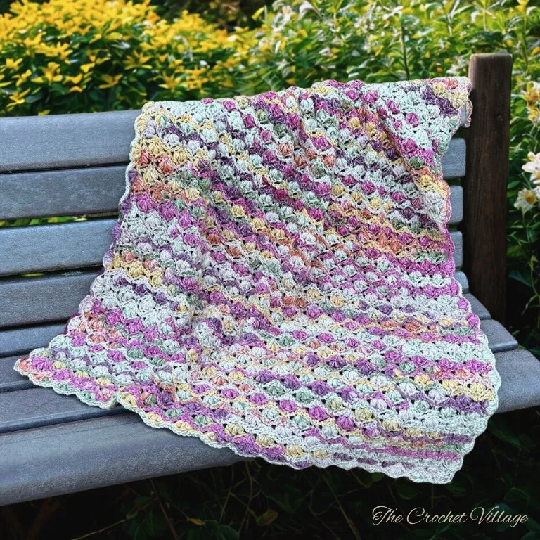 Easy puff stitch crochet blanket draped over a bench, showcasing its cozy texture and elegant design.