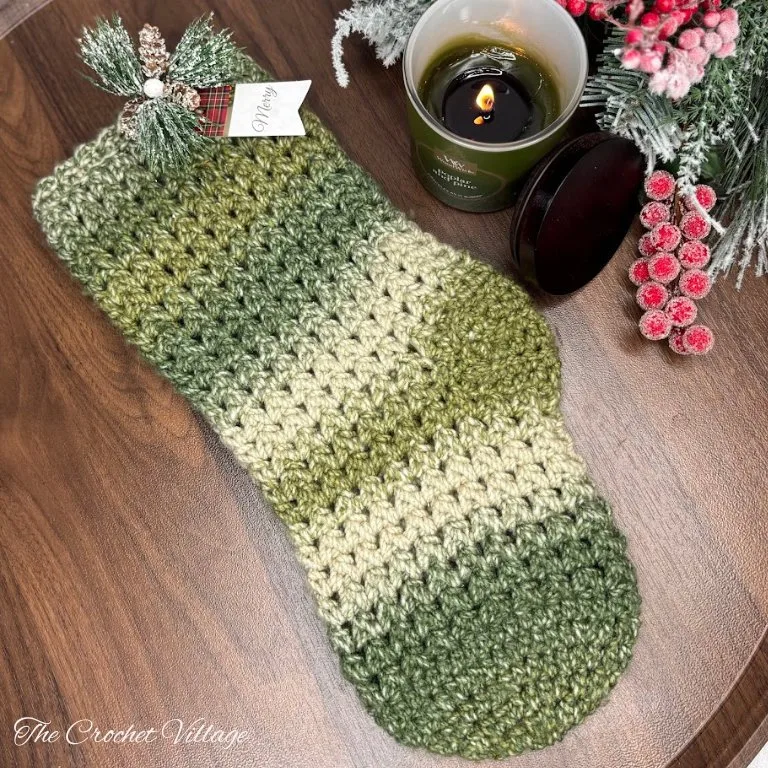 Large textured crochet Christmas stocking hanging on a blanket ladder, surrounded by festive Christmas décor.