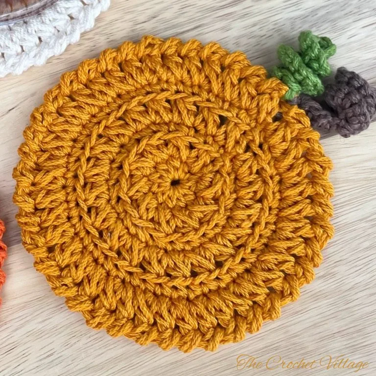Close up of pumpkin-inspired crochet coaster with curly cues