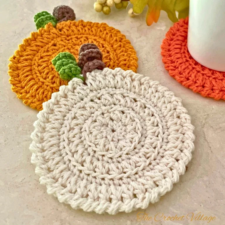 Two pumpkin-inspired crochet coasters in different fall colors displayed with autumn decor