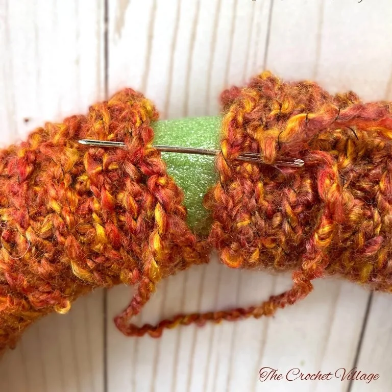 Close-up of crochet piece showing how to sew the two ends of a crochet wreath sleeve