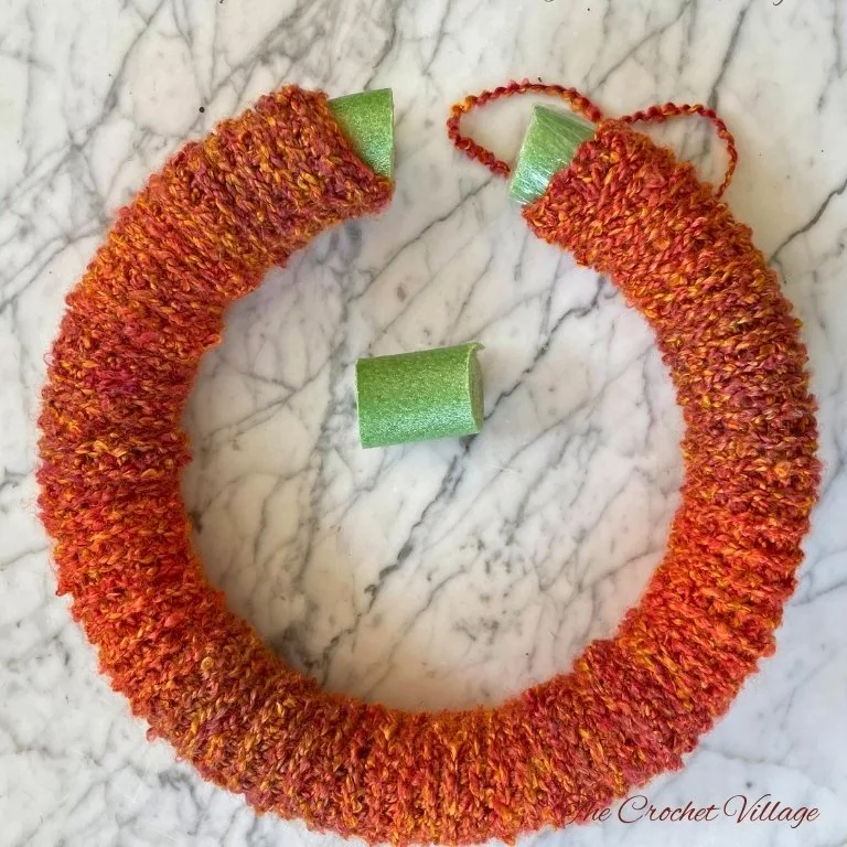 Foam wreath ring covered in crochet sleeve, forming a fall-themed crochet wreath