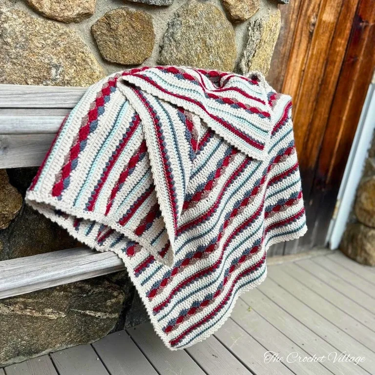 Scrap yarn crochet blanket featuring different colors and stitches draped elegantly on a railing