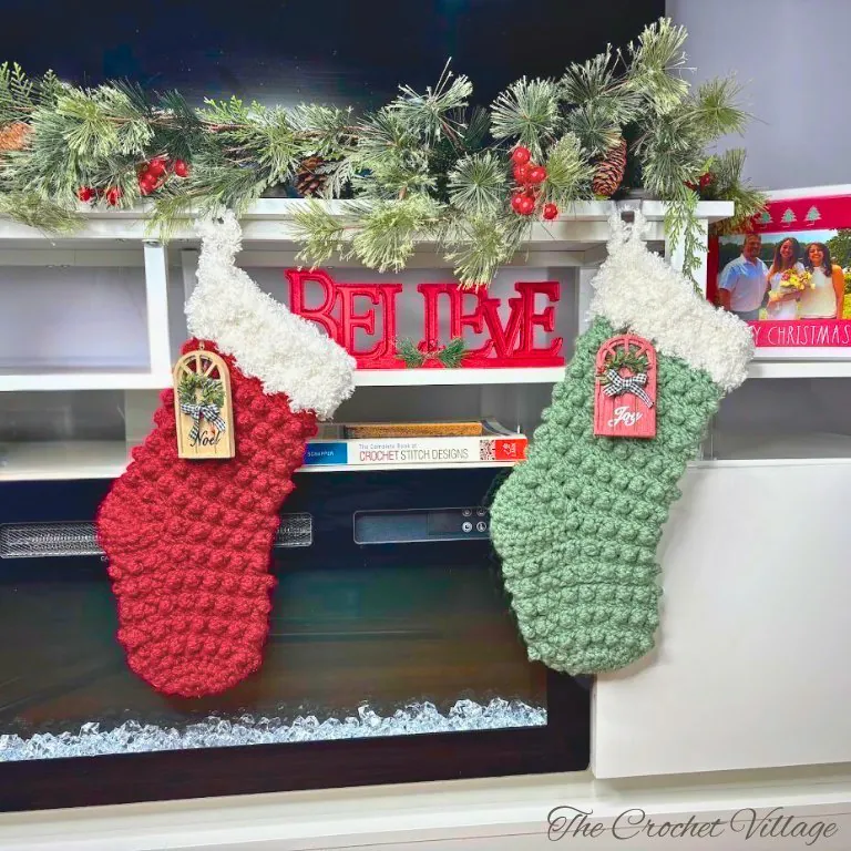 Crochet Christmas stockings on wood table with holiday candle and festive decor