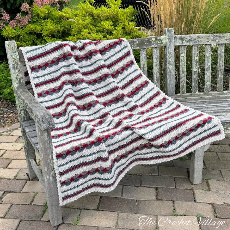 Scrap yarn crochet blanket featuring different colors and stitches draped elegantly on a bench