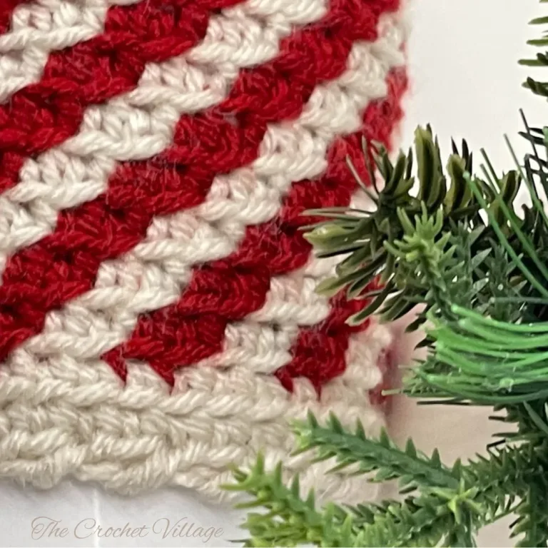Close-up of a crochet piece with striped peppermint colors in red, white,