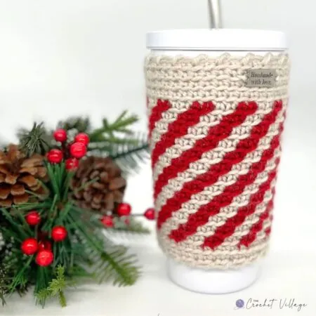 Crochet peppermint cup cozy in festive red and white stripes, designed to enhance grip on stainless steel travel mugs, perfect for Christmas gifting.