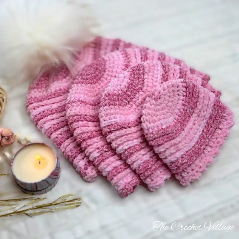 Four handmade crochet chemo hats in pink variegated yarn displayed in different sizes from small to large.