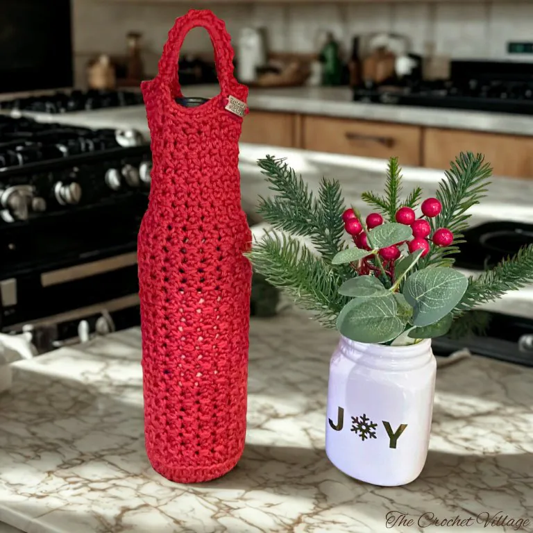 A wine bottle in a crochet bag in a kitchen