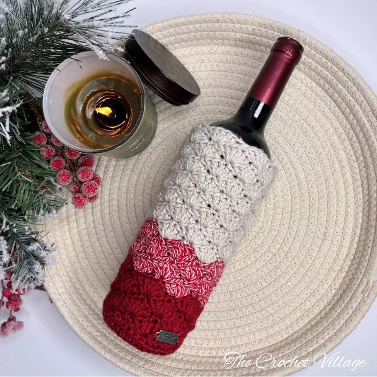 Wine bottle in burgundy crochet carrier using shell stitch with candle and Christmas decorations