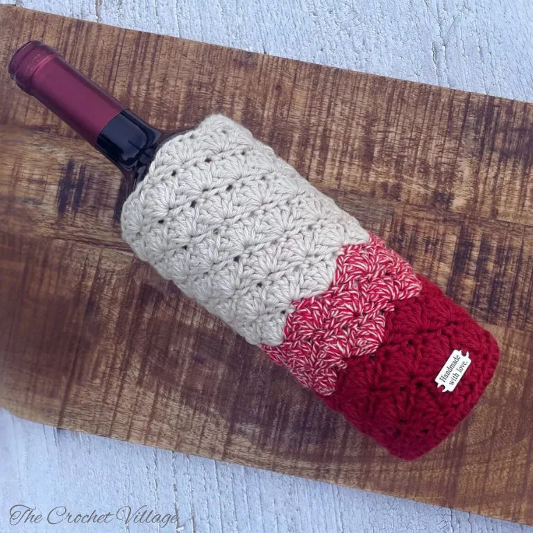 Burgundy crochet wine bottle cover on wooden tray with holiday decorations