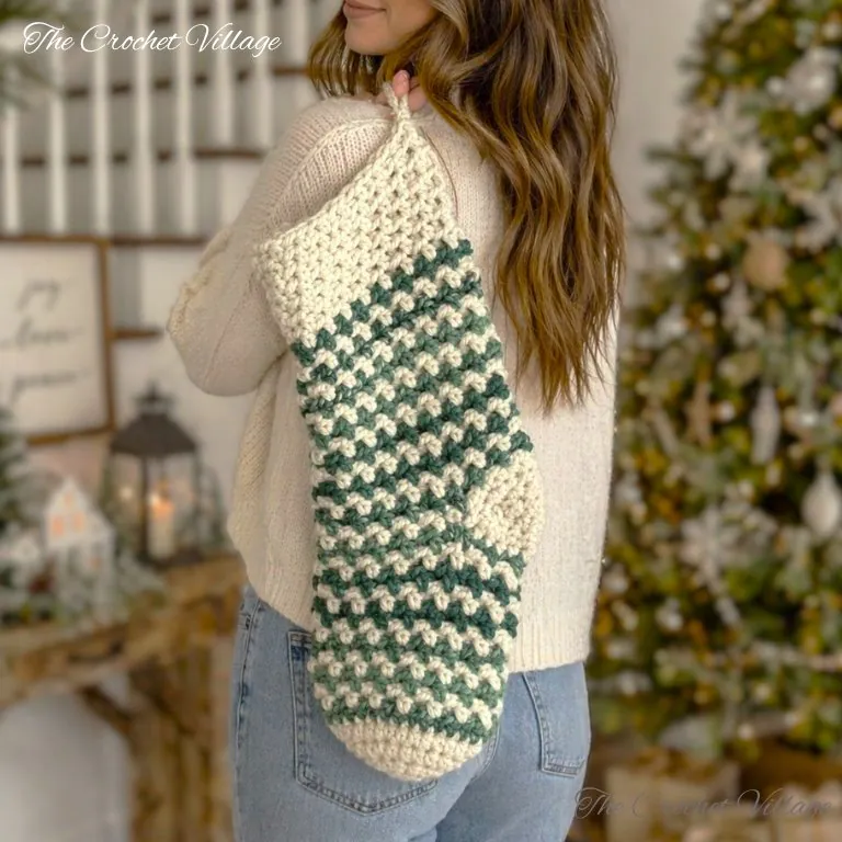 Oversized wintergreen crochet Christmas stocking with textured stitches hanging on mantle next to holiday garland