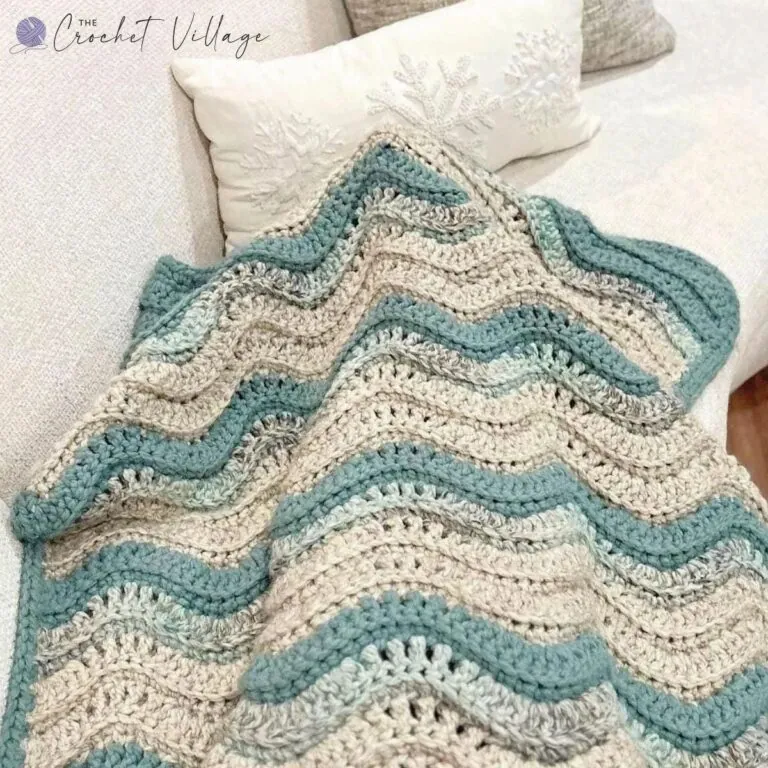 Chunky crochet ripple lap blanket draped across the legs showing the wave texture