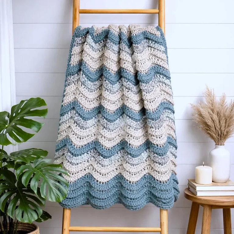 Crochet ripple wave blanket draped over a wooden ladder, showcasing the textured wave pattern and cozy design
