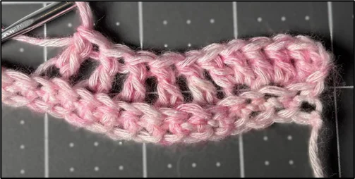 Close-up progress photo showing the start of the ripple chevron crochet stitch, highlighting the first peaks and valleys formed with double crochet stitches
