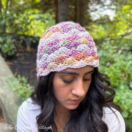A woman wearing a crochet top-down shell stitch hat: The Meadow hat free crochet pattern
