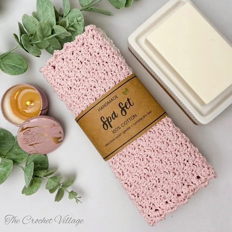 Neatly folded crochet washcloth wrapped in a printable gift wrap with a bar of soap, displayed as a handmade gift set