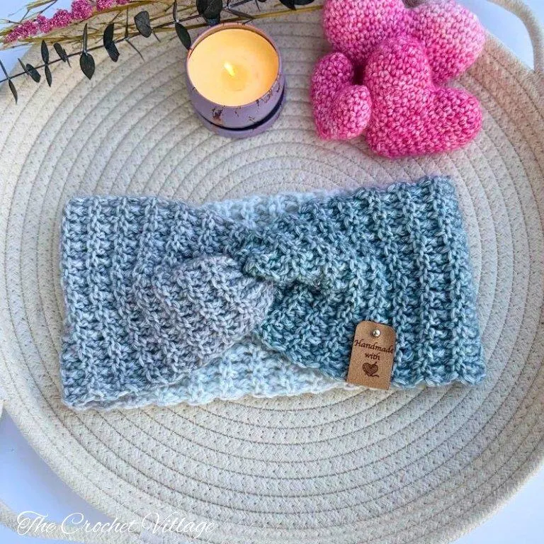 Juliette ear warmer in grey self-striping yarn styled with handmade crochet hearts and candle