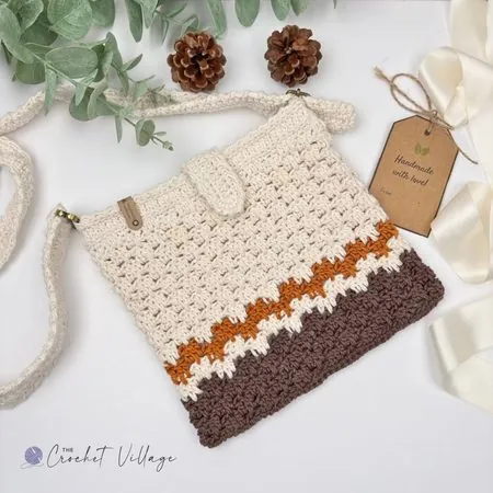 Macchiato crochet crossbody bag laid flat on a denim jacket, handmade messenger purse in cotton yarn