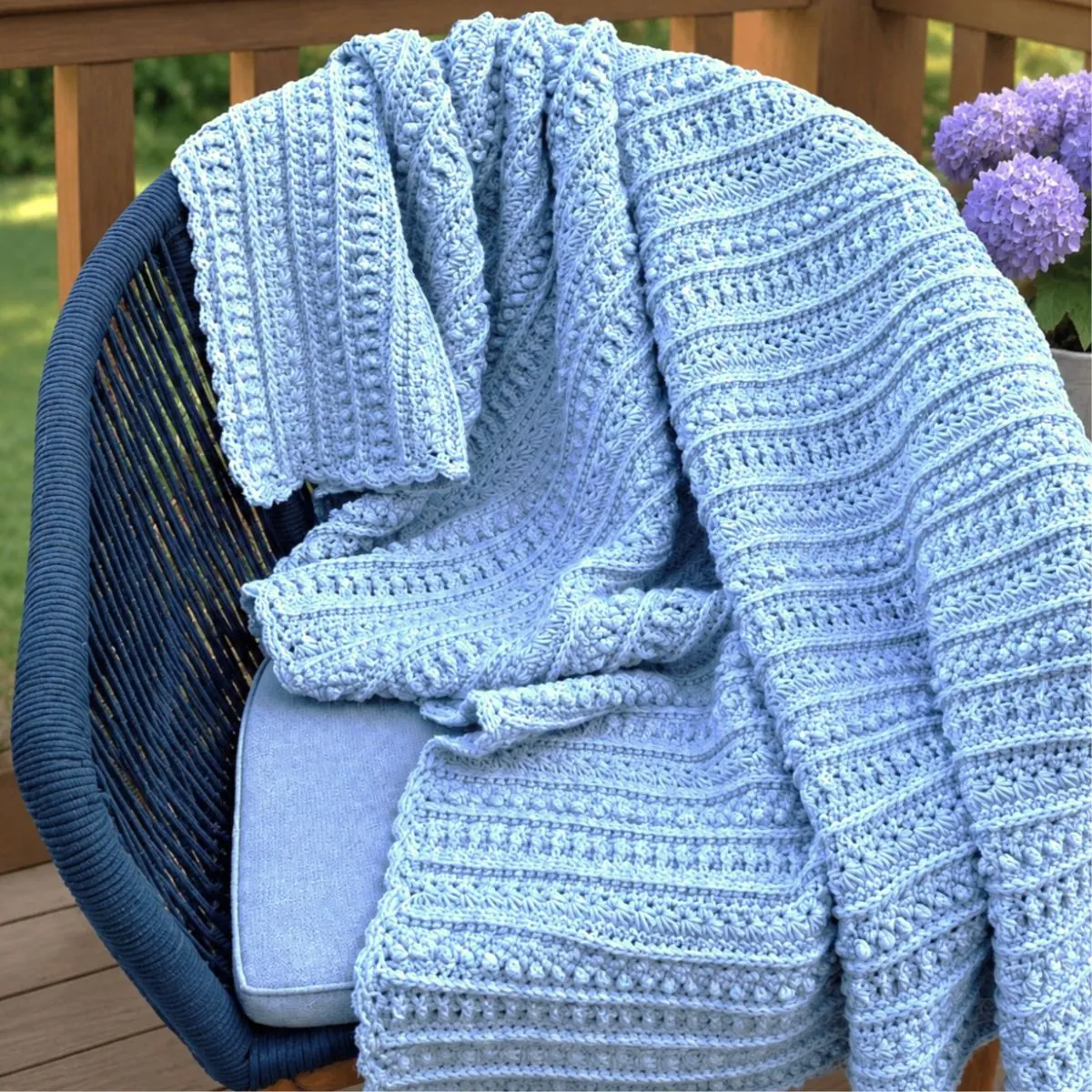 Sterling Blanket free crochet sampler pattern draped over a chair, showing full stitch texture in light blue yarn