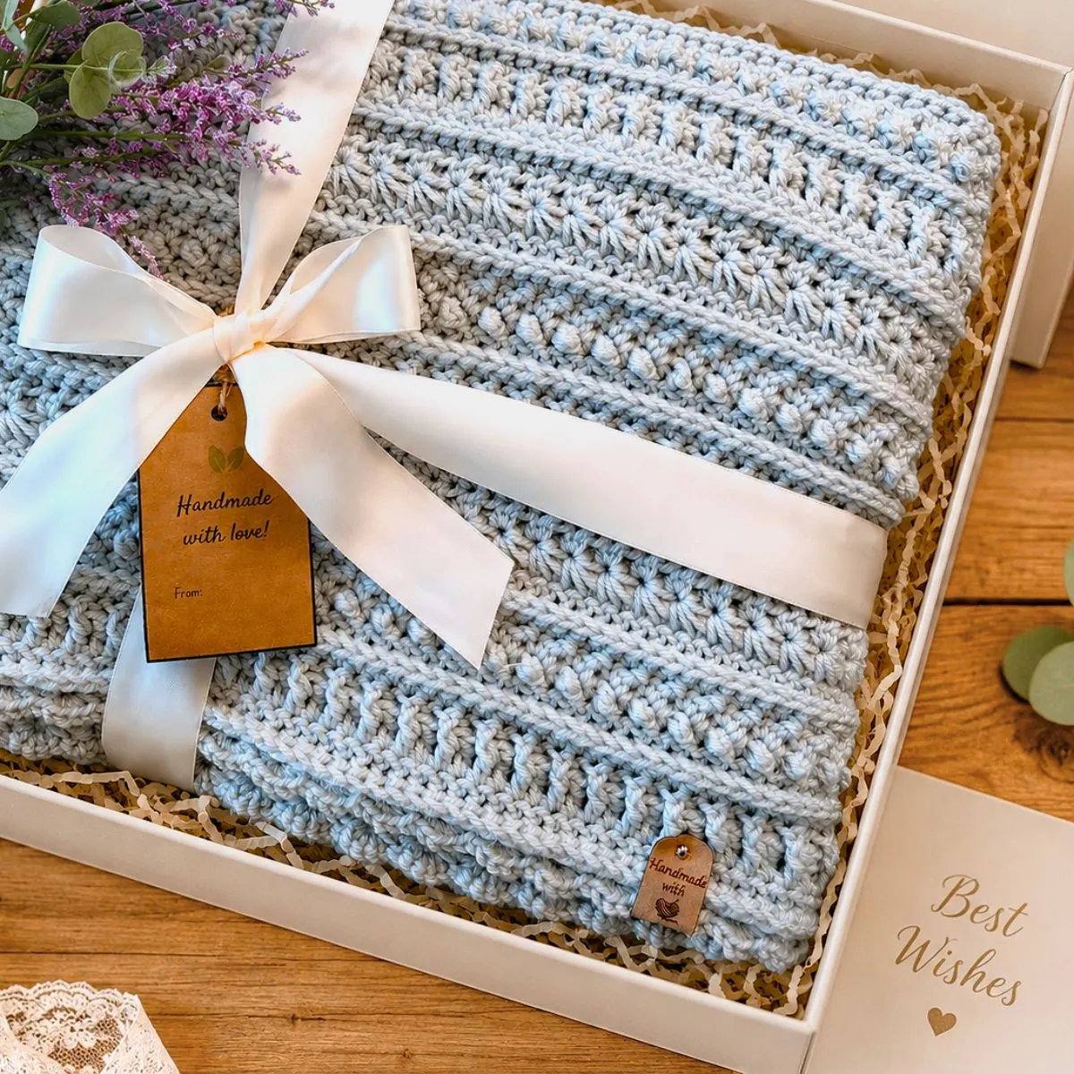 Sterling Blanket free crochet sampler pattern folded in a gift box with ribbon, flowers, and a Best Wishes card