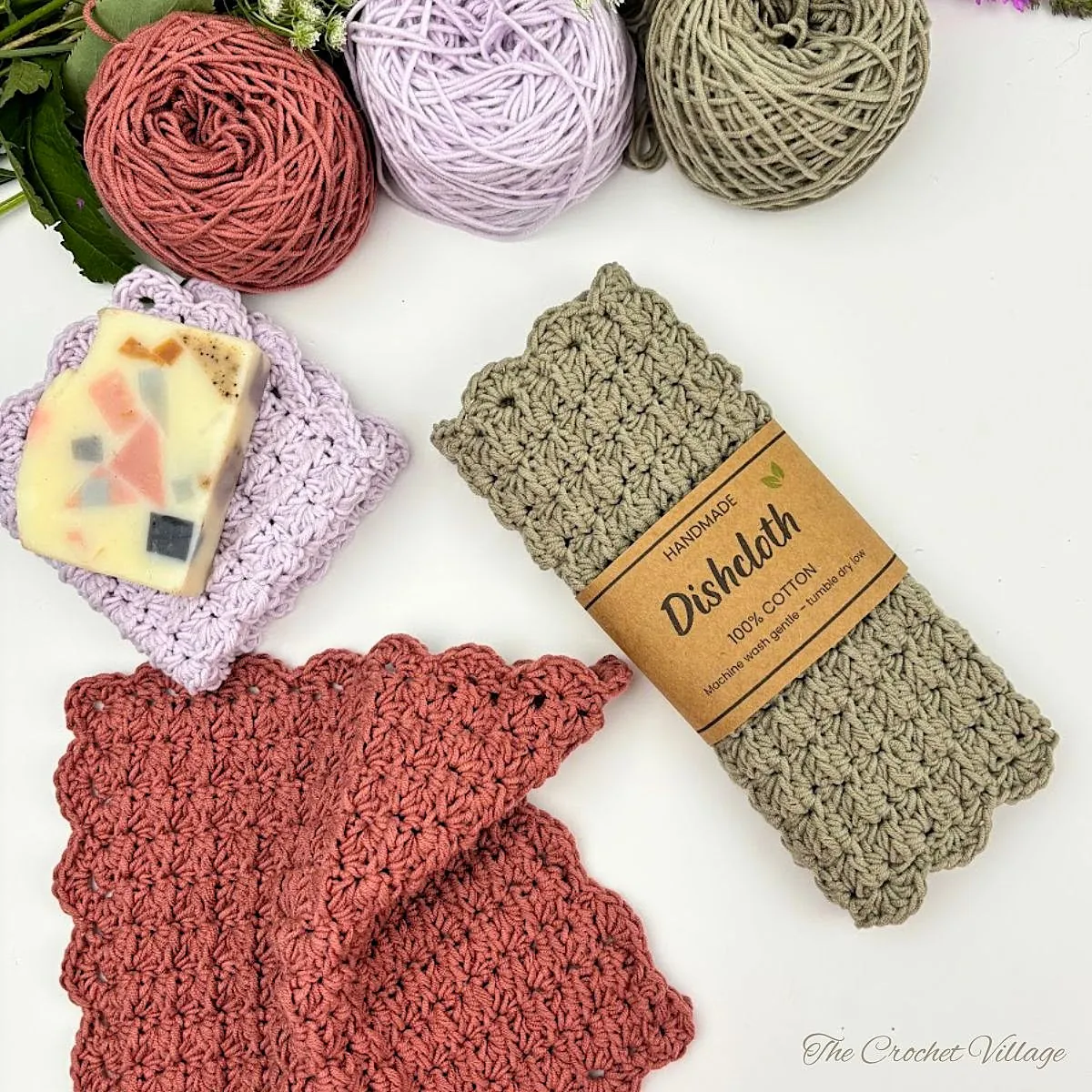 Free crochet dishcloth pattern with scalloped border in lilac, terracotta, and sage cotton yarn, rolled and packaged handmade