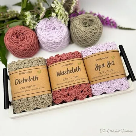 Free crochet dishcloth pattern set in sage, terracotta, and lilac with scalloped border and handmade kraft labels on tray