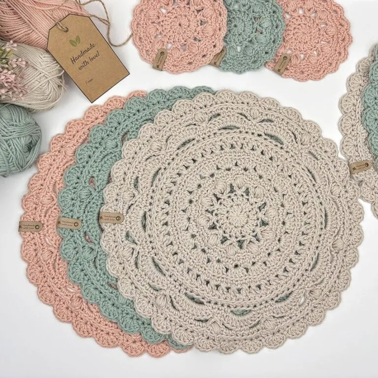 Free crochet placemat pattern shown in cream, sage green, and blush cotton with a scalloped shell border