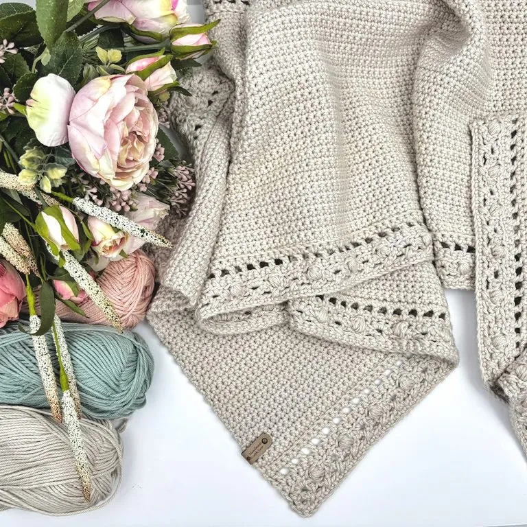 Cream crochet table runner with a puff stitch border, folded beside blush, sage, and cream cotton yarn