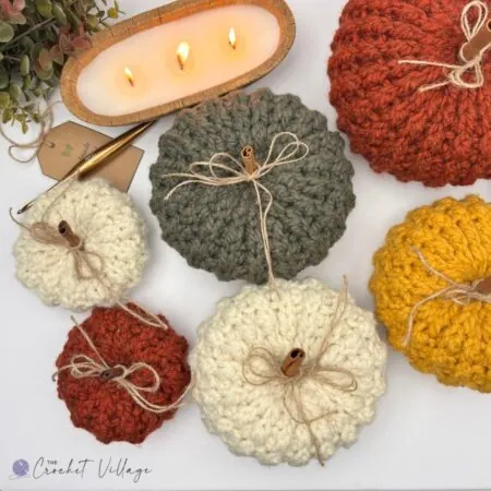 Six chunky crochet pumpkins in cream, sage green, rust orange and mustard yellow with cinnamon stick stems and twine bows — free easy crochet pumpkin pattern in 3 sizes