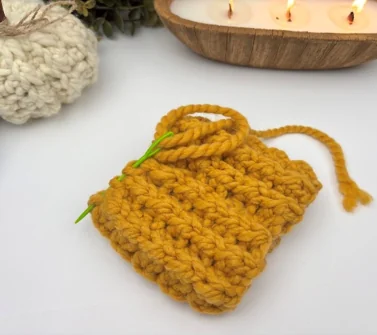 Running stitch threaded around the bottom edge of the crochet tube and pulled tight to gather it closed — crochet pumpkin assembly