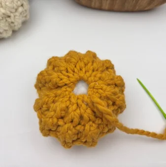 Filling a chunky crochet pumpkin with polyester fiberfill through the open top to shape it- step 2