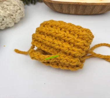 Whip stitching the two short ends of a chunky crochet rectangle together to form a tube — how to crochet a pumpkin step 1