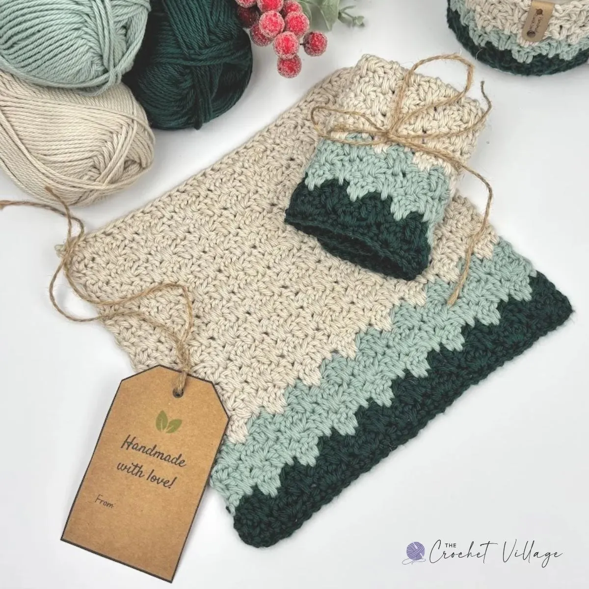 Crochet towel and washcloth set in cream with sage and forest green borders, tied with twine and a handmade gift tag