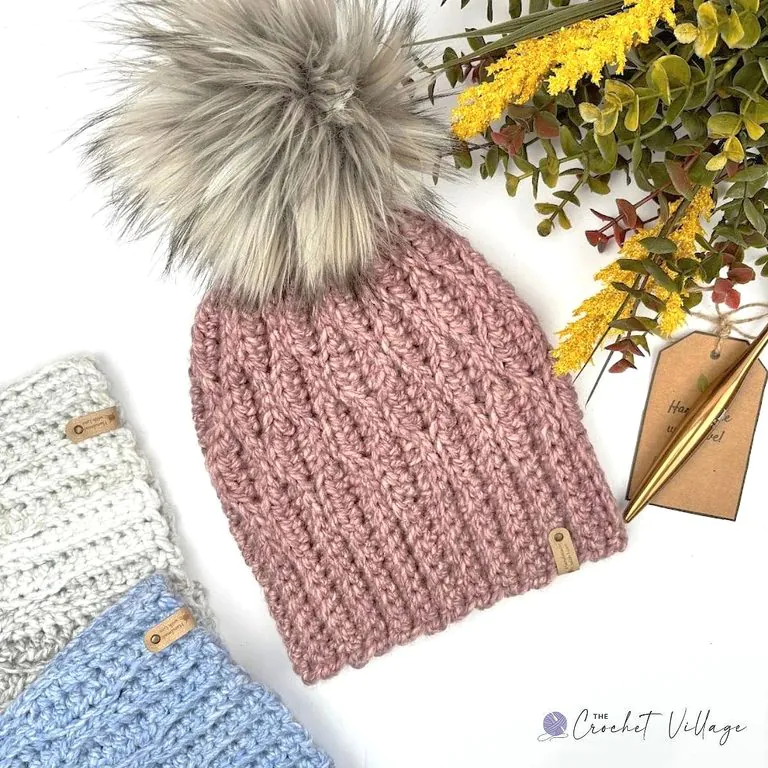 Light Pink crocheted wave-stitch beanie with white pom-pom and handmade tag