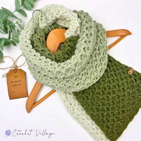 Greenway Scarf free crochet pattern in self-striping green yarn draped over a wooden hanger with a handmade gift tag